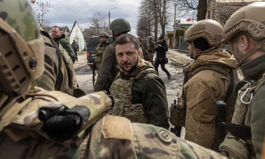 Ukraine’s President Volodymyr Zelenskiy looks on as he is surrounded by Ukrainian servicemen in Bucha, outside Kyiv, Ukraine, April 4, 2022.