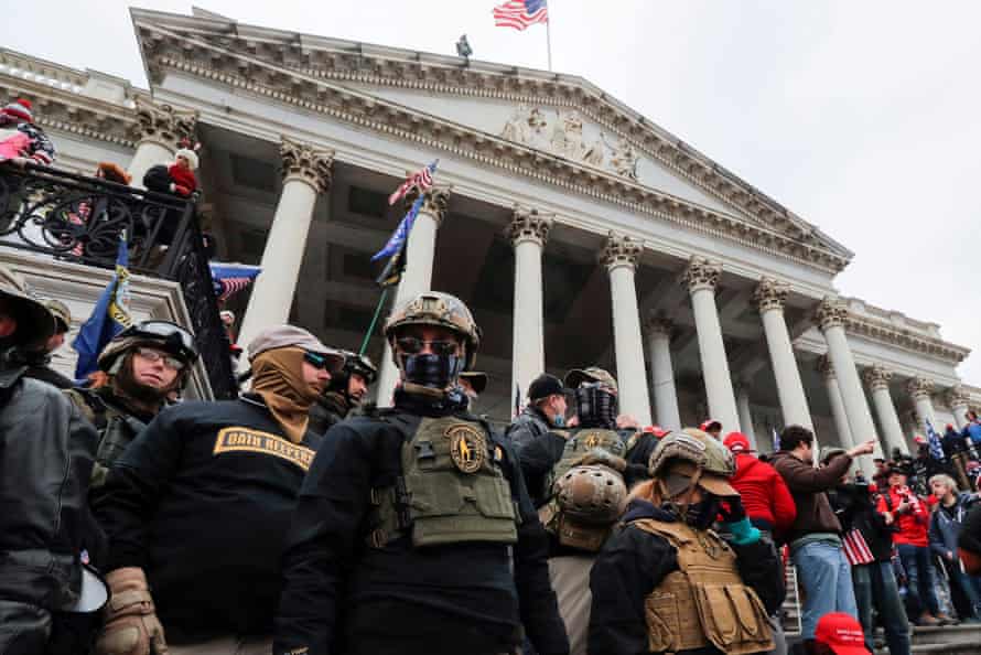 A group of people in military attire stand on the steps in front of the United States Capitol.