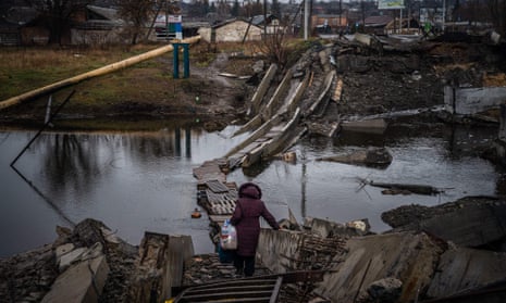 TOPSHOT-UKRAINE-RUSSIA-CONFLICT-WAR<br>TOPSHOT - A woman crosses a destroyed bridge in Bakhmut, Donetsk region, on January 6, 2023, amid the Russian invasion of Ukraine. - Russia and Ukraine have both suffered heavy casualties in the fight for Bakhmut, and most of the city's pre-war population of 70,000 have left for safer territory, leaving behind cratered roads and buildings reduced to rubble and twisted metal. (Photo by Dimitar DILKOFF / AFP) (Photo by DIMITAR DILKOFF/AFP via Getty Images)