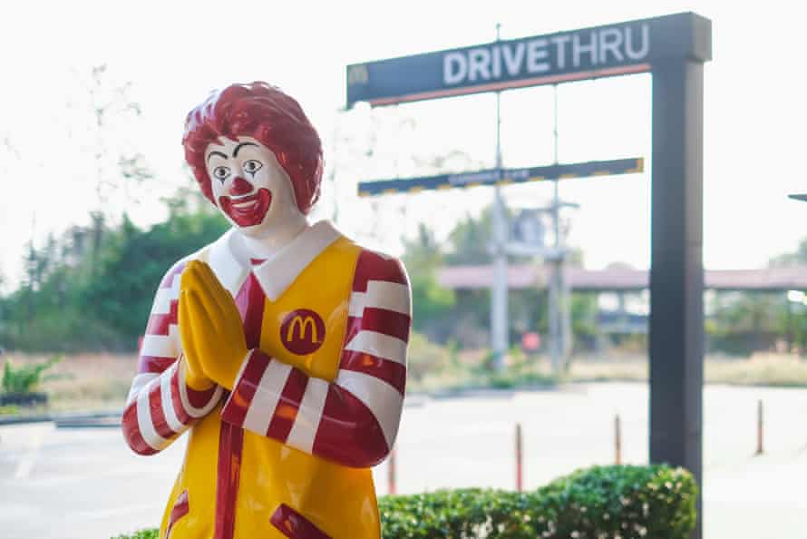 Ronald McDonald figure in front of drive through sign