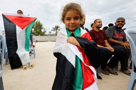 A girl wraps a Palestinian flag around herself as news of Gaza ceasefire deal reaches the central Gaza Strip.