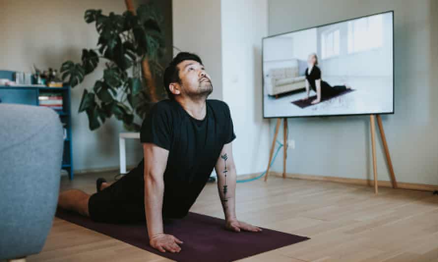 A Japanese man takes an online yoga class in his living room.