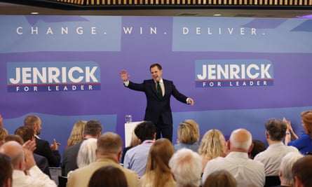 Jenrick in front of an audience, in front of a board bearing the slogan: ‘Change. Win. Deliver.’