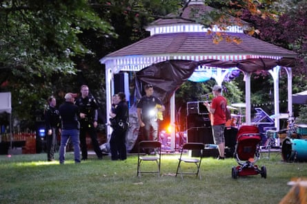 police officers speak with people outside a bandstand set up with band equipment