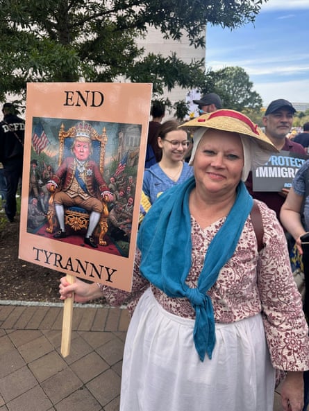 woman at protest holds up sign saying ‘end tyranny’ with a cartoon picture of donald trump as a king