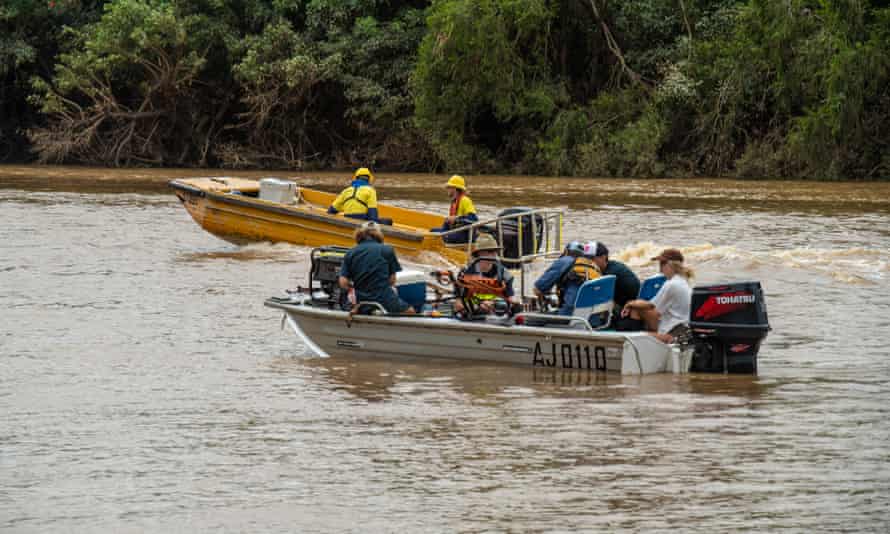 Two small boats with people and supplies on board travel up through murky flood waters in Coraki