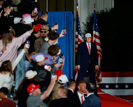 Donald Trump walks between two American flags before a cheering rally crowd