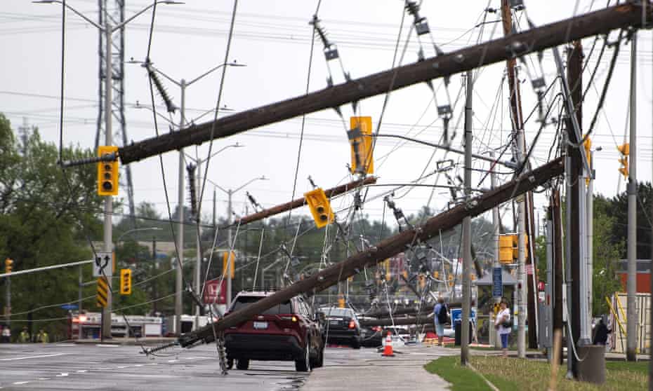 Vehicles are driven among downed power poles in Ottawa, Canada