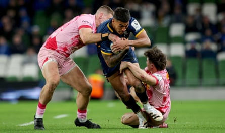 Rieko Ioane is tackled by two Harlequins players.