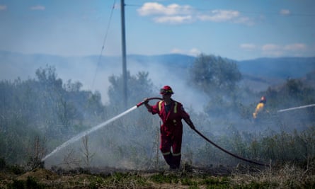 A firefighter directs water on a grass fire burning behind a residential property in Kamloops, British Columbia, Canada, on 5 June.