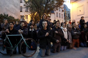 People cry and pray as they look at flames burning the roof of the Notre Dame Cathedral in Paris.