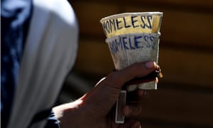 A homeless man holds a cup as he begs in Melbourne