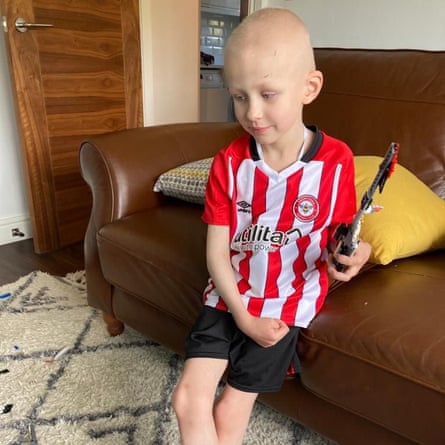 Hugh in a Brentford football shirt on the sofa at home