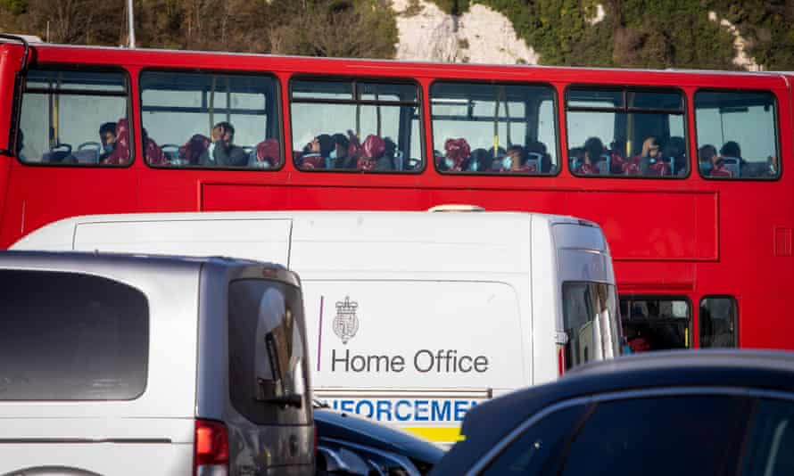People who have just arrived in the UK are put on to a red doubledecker bus outside the Border Force processing centre in Dover