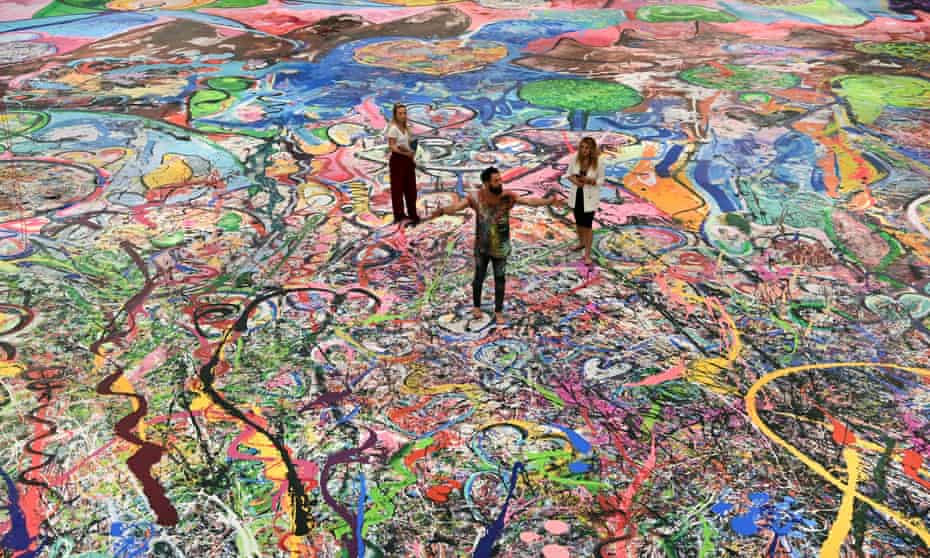 British artist Sacha Jafri (C) stands on his record-breaking painting entitled ‘The Journey of Humanity’ in the Emirati city of Dubai.