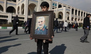 A boy in Tehran holds a portrait of Qassem Soleimani.