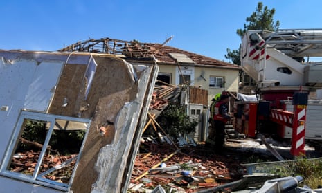 Firefighters work at the site of a damaged house