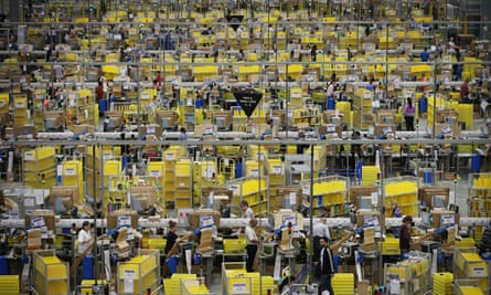 Scene shot from above of a huge warehouse floor full of rows of sorting equipment and workers assembling shipments