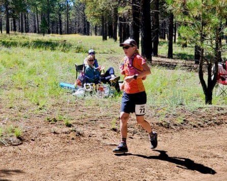a woman runs on a dirt trail near trees