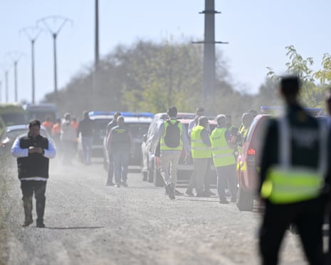 Emergency workers in high-visibility vests gather near vehicles at a train collision site