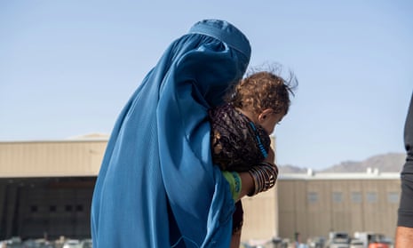A woman carries a child on to an evacuation flight at Hamid Karzai International Airport in Kabul.