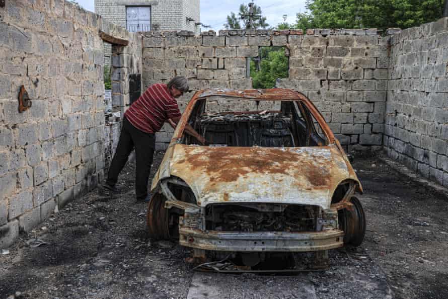 Yekaterina Yorkovets, 58, whose house was completely destroyed, inspects a damaged car in the village of Zahaltsi in the Kyiv region on Sunday