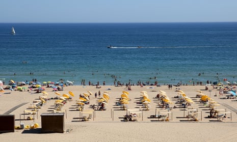 Beachgoers sunbathe and swim at a beach in Portimao, Portugal.