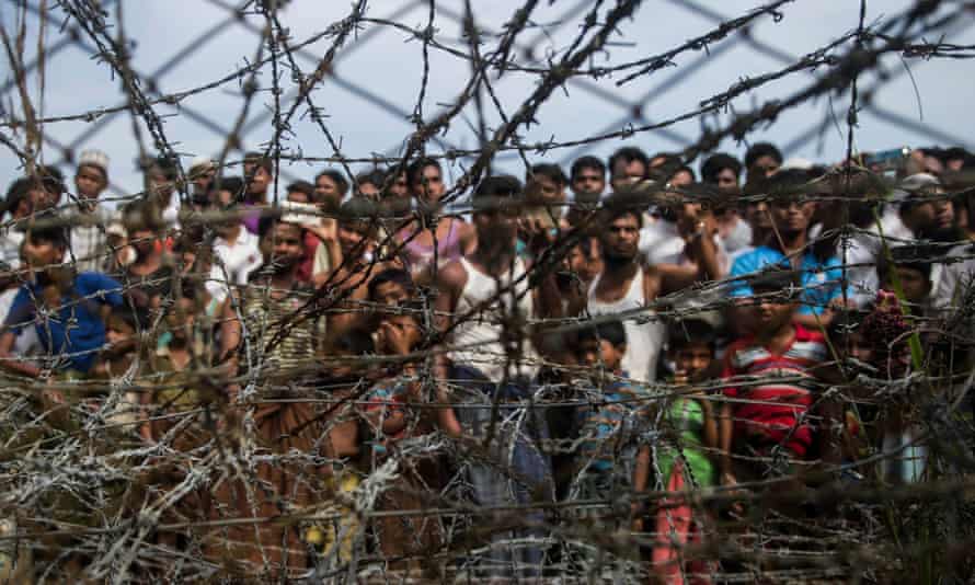 Rohingya refugees gather behind a barbed-wire fence in a temporary settlement in a “no man’s land” border zone between Myanmar and Bangladesh, April 2018