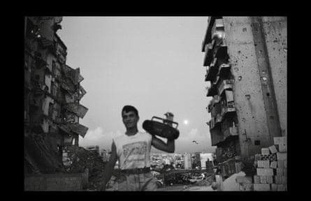 A man holds up a boombox in a bombed out street in Lebanon.
