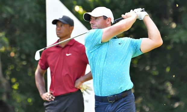 Rory McIlroy hits his tee shot as Tiger Woods looks on during The Northern Trust golf tournament last year