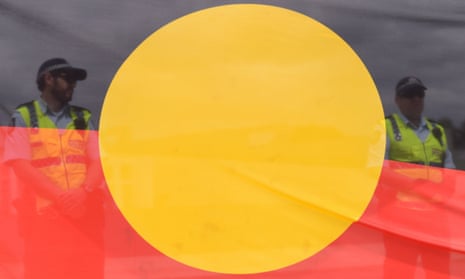 An Indigenous flag with policemen behind it