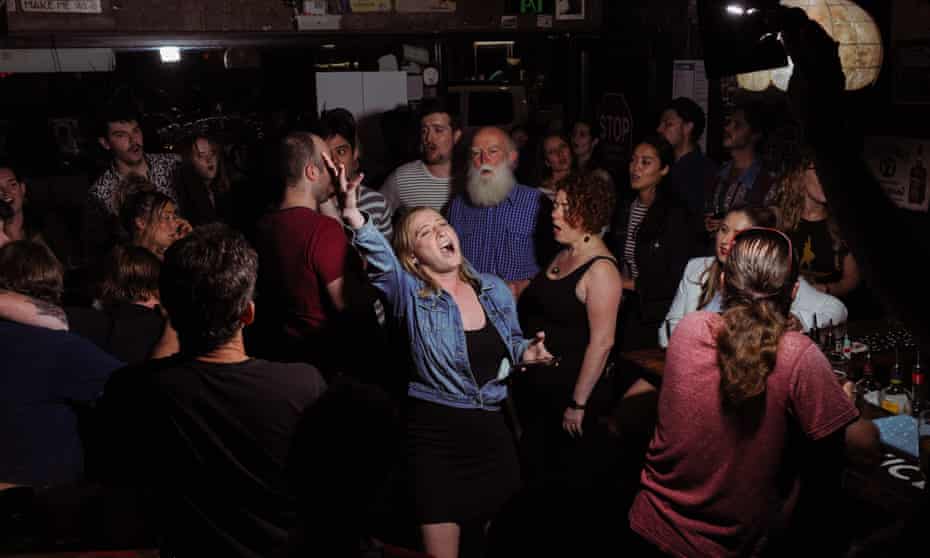 Emma Norton sings in the center of a crowd