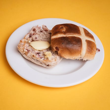 An Asda Exceptional cherry bakewell hot cross bun, sliced, toasted and buttered, on a white plate