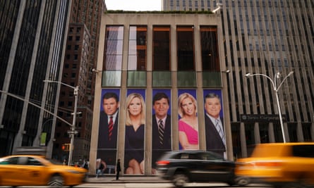 Traffic on Sixth Avenue, NY passes by ads featuring Fox News personalities, including Bret Baier, Martha MacCallum, Tucker Carlson, Laura Ingraham, and Sean Hannity, on the front of the News Corporation building.