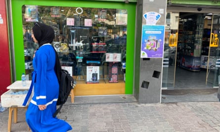 A Gaza woman passes by a shop selling PlayStation5 consoles