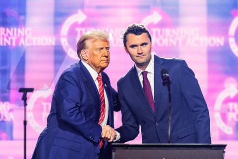 two men in suits shake hands on stage
