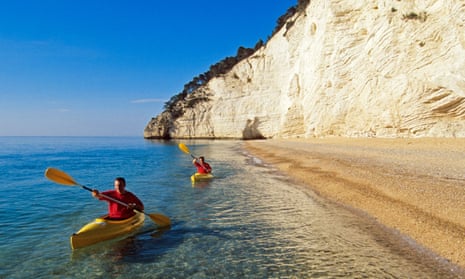 Kayaks on clear sea under white cliffs