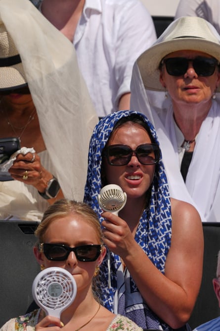 People use fans against the heat at a tennis match in London