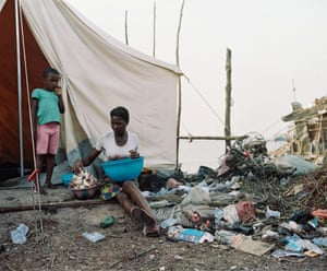 A woman and child outside a tent surrounded by rubbish