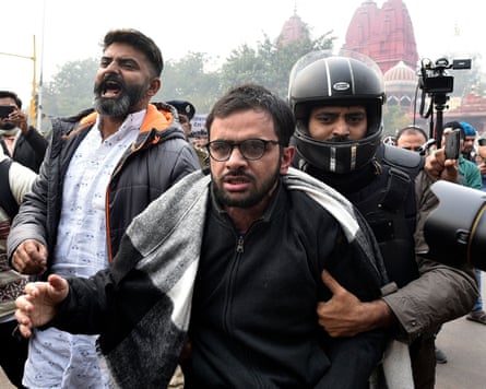 Umar Khalid is held from behind by a person wearing a black helmet
