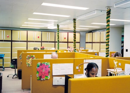 People sitting at desks behind yellow partitions in an office, with Christmas decorations stuck up around them