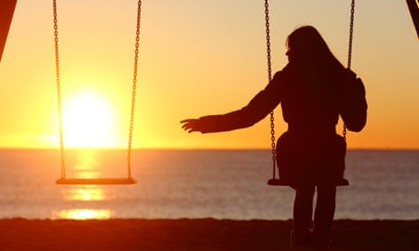 A woman alone on a swing reaching out to empty swing beside her