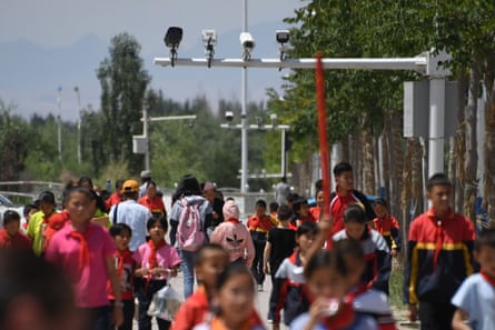 Children pass cameras in Akto, near Kashgar, Xinjiang, where China’s Uighurs face intense surveillance. Cameras can tell Uighurs from Han Chinese.