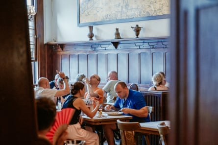 View through a door into wood-panelled room with many drinkers