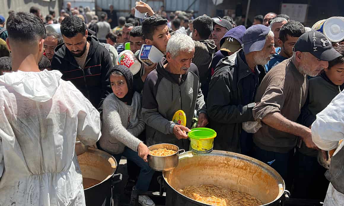 Amid Israel’s continued aid blockade, which began 2 March, Palestinians receive meals distributed by charities in the Nuseirat refugee camp on Tuesday.