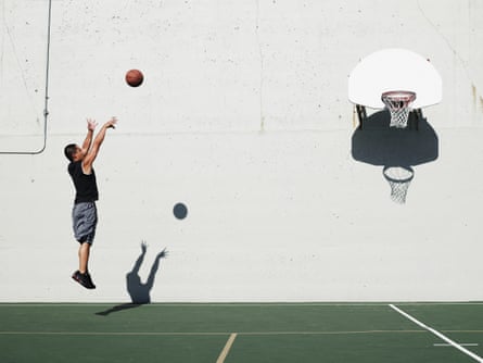 A man jumps to throw a basketball into a hoop.
