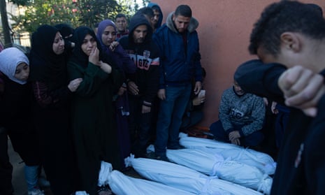 Relatives of Palestinians from a family killed in an Israeli airstrike mourn next to their wrapped bodies outside Nasser hospital in Khan Younis