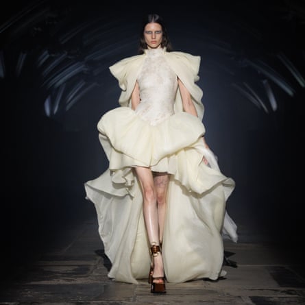 A model wearing a cream mini dress adorned with puffy organza sleeves and overskirt