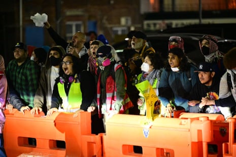 Protesters stand behind orange barriers outside Delaney Hall immigration detention center at night