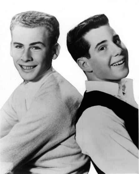 Black and white photo of the pair back-to-back, with flat-top haircuts and clean-cut looks